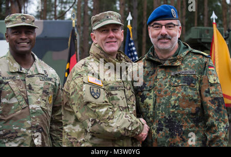 GRAFENWOEHR, Germany – U.S. Army Brigadier General Steven Ainsworth (center left), Deputy Commanding General of the 21st Theater Sustainment Command, shakes hands with Major General Ulrich Baumgartner (right), Commanding General of the Bundeswehr Operational Medical Support Command, after signing the first ever unit memorandum of partnership during a U.S. Army Europe Expert Field Medical Badge evaluation in Grafenwoehr, Germany on March 24, 2017. Approximately 215 candidates from the U.S. Army and ten European partner nations attended this biannual evaluation in hopes of achieving the coveted  Stock Photo