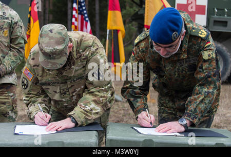 GRAFENWOEHR, Germany – U.S. Army Brigadier General Steven Ainsworth (left), Deputy Commanding General of the 21st Theater Sustainment Command, and Major General Ulrich Baumgartner (right), Commanding General of the Bundeswehr Operational Medical Support Command, sign the first ever unit memorandum of partnership between the two commands during a U.S. Army Europe Expert Field Medical Badge evaluation in Grafenwoehr, Germany on March 24, 2017. Approximately 215 candidates from the U.S. Army and ten European partner nations attended this biannual evaluation in hopes of achieving the coveted U.S.  Stock Photo