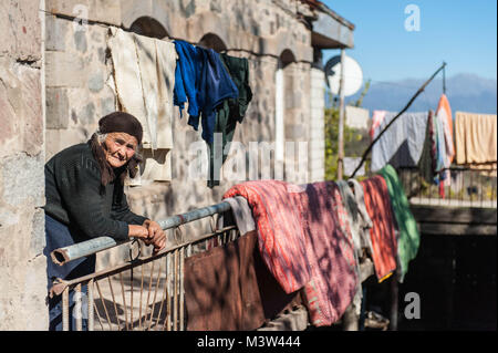 Poor old woman standing on the balcony of her house in Khndzoresk rural community in the South-East of Armenia. Stock Photo