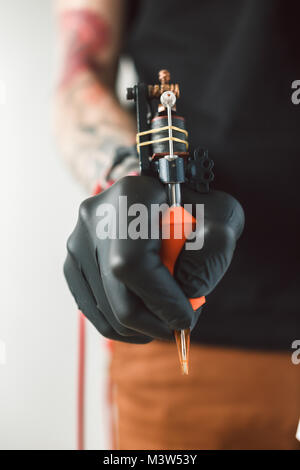 master's hands hold a tattoo machine. Stock Photo