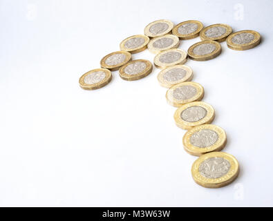 Several new twelve sided British pound coins arranged in the shape of an arrow denoting an upward trend Stock Photo