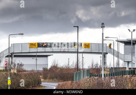 Two male workres crossing a metal foot bridge onto Sports Direct main distribution warehouse at Shirebrook, derbyshire. Stock Photo