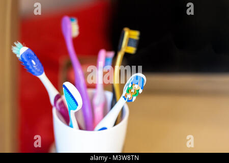 White glass with lots multicolored toothbrushes. Dental care and  oral hygiene. Tongue cleaning. Big family concept Stock Photo