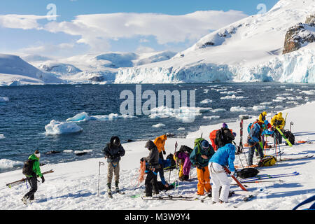 Ski mountaineers roped together for safety from crevasses use synthetic skins on skis to climb uphill; RongÃ© Island; Arctowski Peninsula; Antarctica Stock Photo