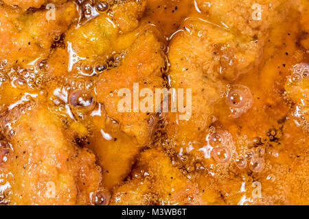 Frying the meat wrapped in breadcrumb on the pan, close up. Fried chicken in oil. Stock Photo