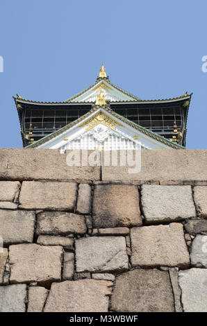 Looking up at the roof of Osaka Castle, from below stone wall. Oriental design and architecture. Popular tourist destination - at Osaka, Japan Stock Photo