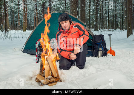 a tourist in a winter forest in extreme conditions is building a fire Stock Photo