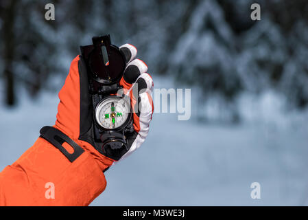 hand with a compass in the frost on a snowy forest background Stock Photo
