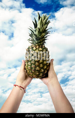 pineapple in hands against the blue sky Stock Photo