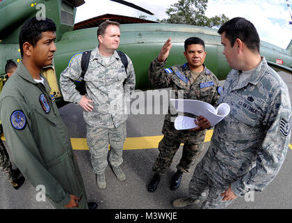 Honduran Air Force Sub-official Master 1st Class Juan Carlos Rodriguez Rivas, helicopter flying crew chief, and Senior Master Sgt. Jason Hood, 571st Mobility Support Advisory Squadron helicopter crew chief and air advisor, listens in as FAH Sub-official Master 2nd Class Enrique Hernandez Sanchez, FAH inspector, and Technical Sgt. Ruben Sigala, Inter-American Air Forces Academy instructor, discusses the inflight operational check of the radar altimeter system at Col. Hernán Acosta Mejia Air Base, Tegucigalpa, Honduras, Feb. 6.  (U.S. Photo by Tech. Sgt. Lesley Waters) US, Honduran Air Forces wo Stock Photo