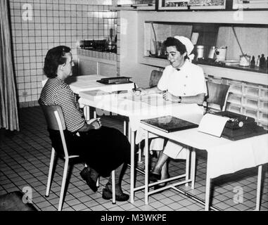 Old black and white archival photograph showing female factory worker visiting nurse at dispensary in the 1950s Stock Photo