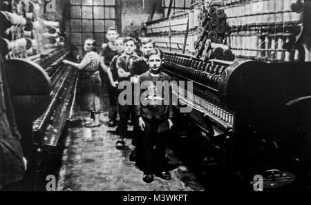 Old black and white archival photograph showing female worker and child labourers posing in spinning mill in the early twentieth century Stock Photo