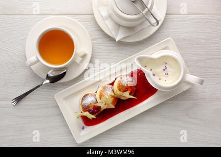 Cottage cheese pancakes with strawberry jam, sour cream on white wooden background, breakfast or lunch, tea Stock Photo