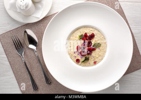 oatmeal porridge with dried fruits on white wooden background, breakfast Stock Photo