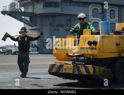 ARABIAN GULF (Aug. 8, 2017) U.S. Marine Corps Lance Cpl. Dakota Buer, left, from Milwaukee, watches as U.S. Navy Airman Thomas Logie, from Clio, Mich., uses a mobile vacuum unit, commonly known as the 'Scrubby', to clean the flight deck of the aircraft carrier USS Nimitz (CVN 68), Aug. 8, 2017, in the Arabian Gulf. Nimitz is deployed in the U.S. 5th Fleet area of operations in support of Operation Inherent Resolve. While in this region, the ship and strike group are conducting maritime security operations to reassure allies and partners, preserve freedom of navigation, and maintain the free fl Stock Photo