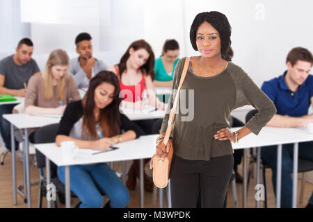 Portrait Of A Happy Student Standing In Classroom Stock Photo