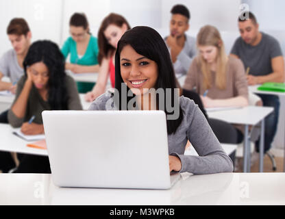 Portrait Of A Smiling Female Student Using Laptop Stock Photo