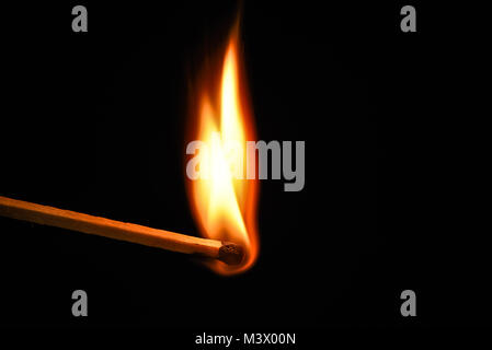 Fire burning on matchstick. Isolated on black background. Macro Stock Photo