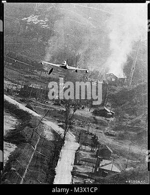 Korean War Pictures - An F-80 Dropping Napalm Bombs at Suan  This dramatic photo of a U.S. Air Force F-80 Shooting Star fighter-bomber has captured the action which occurred May 8 when day-long flights of Fifth Air Force warplanes blasted the Communist two-square mile supply center at Suan in the largest single air strike of the Korean conflict. The storage area, 35 miles southeast of Pyongyang, was smothered with more than 12,000 gallons of napalm dropped by the attacking planes. In this photo a tank of napalm can be seen just after being released. It is below the left wing of the jet. Target