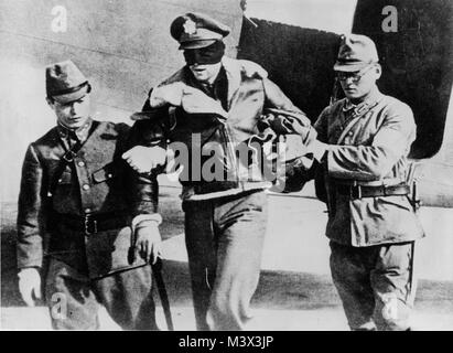 In a photograph found after Japan's surrender in 1945, Lt. Robert L. Hite, copilot of crew 16, is led blindfolded from a Japanese transport aircraft after his B-25 crash landed in a China after bombing Nagoya on the the 'Doolittle Raid' on Japan and he was captured. He was imprisoned for 40 months, but survived the war. Doolittle Raider RL Hite blindfolded by Japanese 1942 by AirmanMagazine Stock Photo