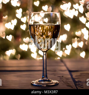 Cheers to wine lovers everywhere! Heart-shaped bokeh with Christmas tree in background. Stock Photo