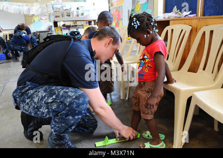 110421-F-CF975-036 KINGSTON, Jamaica (April 21, 2011) Aviation Ordnanceman 3rd Class Robert Noonan, from South Boston, N.Y., fits a student for shoes during a Continuing Promise community service project. Samaritan's Feet, a non-governmental organization, donated the shoes. Continuing Promise is a five-month humanitarian assistance mission to the Caribbean, Central and South America. (U.S. Air Force photo by Senior Airman Kasey Close/Released) Continuing Promise mission in Jamaica by ussouthcom Stock Photo