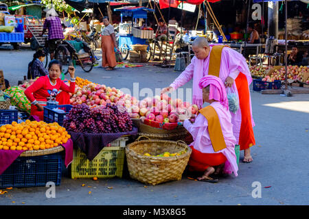 Two buddhist nuns are buying apples at the vegetable market in the streets of town Stock Photo