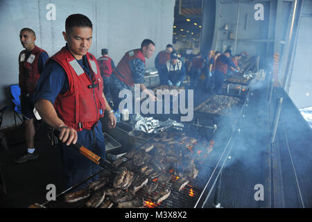 PUGET SOUND, Wash. (July 31, 2014) Chief Fire Controlman Ricky B. Padua, from Las Vegas, Nev., cooks ribs for a steel beach picnic aboard the aircraft carrier USS Nimitz (CVN 68) during a Friends and Family Day Cruise. Nimitz returned to Naval Station Everett after hosting more than 400 friends and family members during a one-day cruise. (U.S. Navy photo by Mass Communication Specialist 3rd Class Eric M. Butler/Released) 140731-N-UV347-116.JPG by USS NIMITZ (CVN 68) Stock Photo