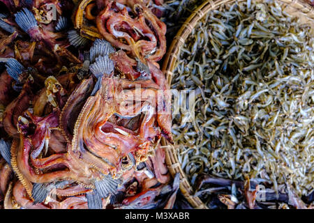 Dried fish, packed in bamboo baskets, is for sale at the vegetable market in the streets of town Stock Photo