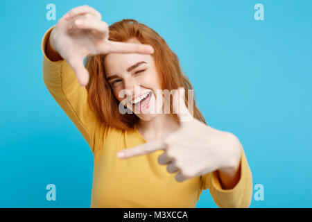 Portrait of young beautiful ginger woman with freckles cheerfuly smiling making a camera frame with fingers. Isolated on white background. Copy space. Stock Photo