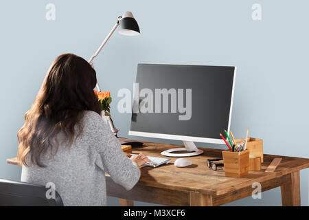 Rear View Of A Woman Working On Computer With Blank Screen Stock Photo