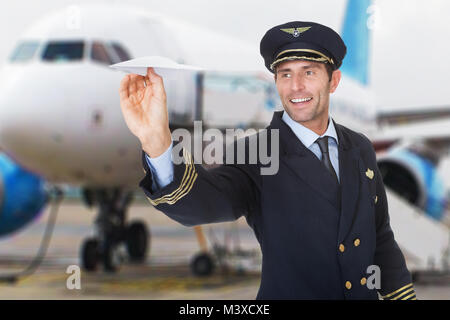 Portrait Of A Smiling Male Pilot Flying Paper Airplane Stock Photo