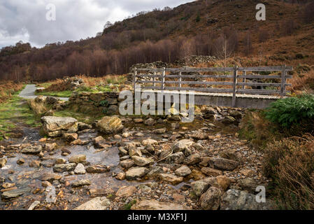 Footbridge over rocky stream beside Llyn Dinas, Snowdonia national park, Bedggelert, North Wales. Stock Photo