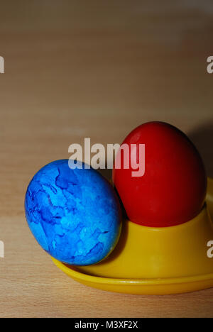 brightly painted red and blue easter egg for easter in egg cup horizontal format Stock Photo