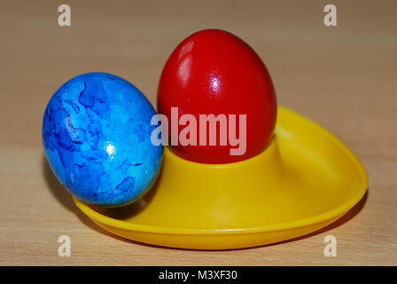 brightly painted red and blue to yellow easter easter egg in egg cup Stock Photo