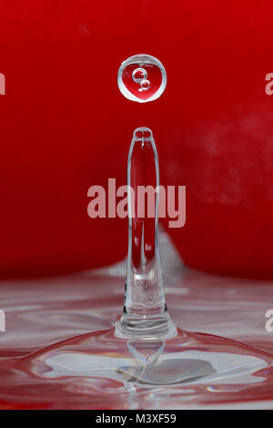 impacting drop with red heart reflection in drop Stock Photo