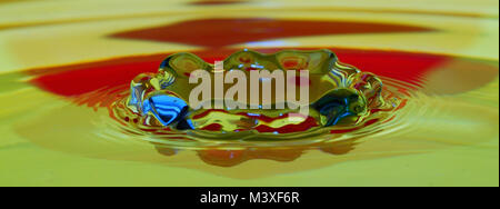 drops impacting water panorama view in red yellow Stock Photo