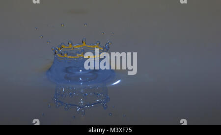 impacting drop in blue liquid orange with blue crown Stock Photo