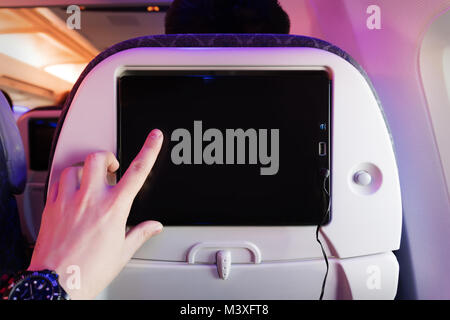 Aircraft monitor the passenger seat. Interior plane. Touch screen. male finger taps on the screen. blank form for design. empty screen. entertainment  Stock Photo