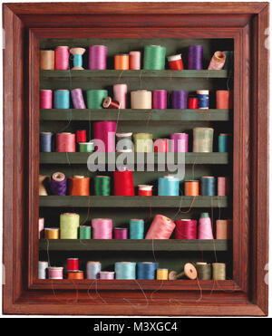 Sewing spools in frame, vertical color photograph of various vintage, spools in a vertical color studio photograph, some used, with drooping threads Stock Photo