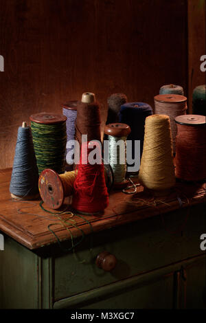 Multiple weaving spools with cotton or wool thread on them.  Vertical color photograph shot in a studio setting with dramatic lighting.  Dark earthy Stock Photo