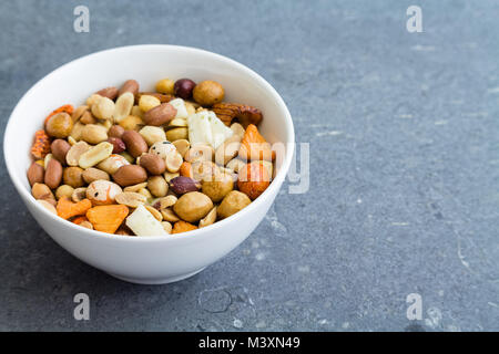 Nuts and seeds in white bowl on dark grunge texture background Stock Photo