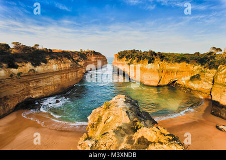 Overlooking secluded tiny Loch Ard Gorge beach in Twelve Apostles marine park on Shipwreck coast of Victoria, Australia. Warm morning light illuminate Stock Photo