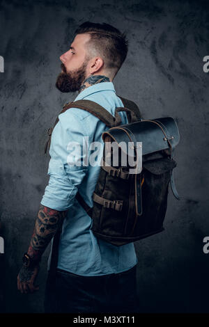 Bearded tattooed backpacker posing in studio. Stock Photo