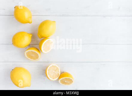 Arrangement of whole and halved lemons on light gray wood background. Top view. Stock Photo