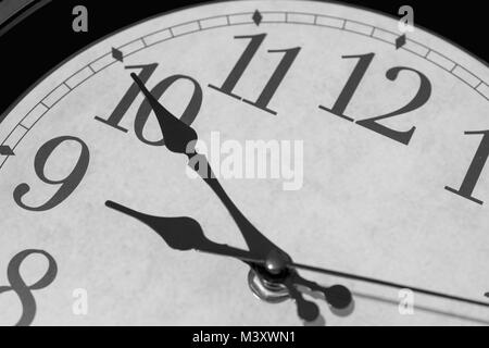 Closeup on the pointers of a clock marking ten minutes before nine o’clock - black and white rendering. The main focus is on the hour and minute point Stock Photo