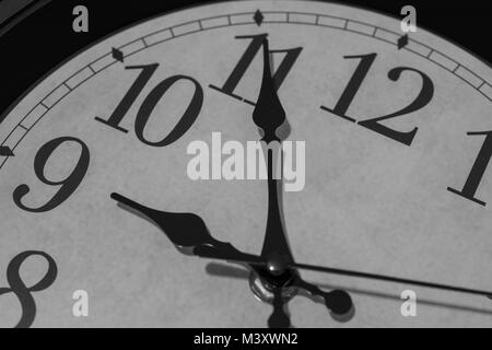 Closeup on the pointers of a clock marking five minutes before nine o’clock - black and white rendering. The main focus is on the hour and minute poin Stock Photo