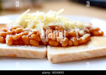 Baked beans on white toast topped with grated cheddar cheese Stock Photo