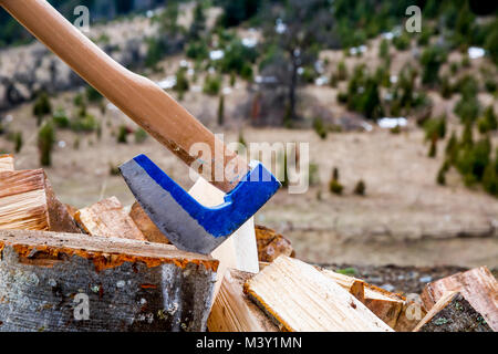 Axe stuck in a beech stub with wood blocks as background. On the mountain Stock Photo