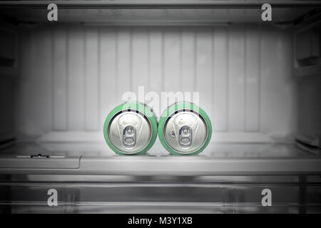 Two cans of beer lie in an empty fridge. Dewy cans with beer on a shelf in the refrigerator. Stock Photo